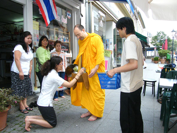 Bhante Medhayo bekommt Speisen als Spenden, links in derTür Noy, die Chefin des kleinen Asia-Shops